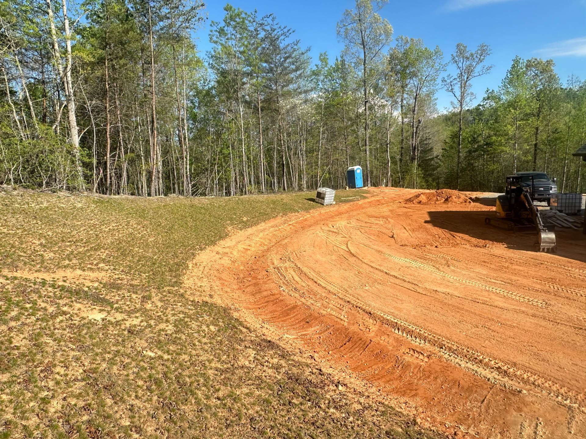 A dirt road going through a grassy field with trees in the background.