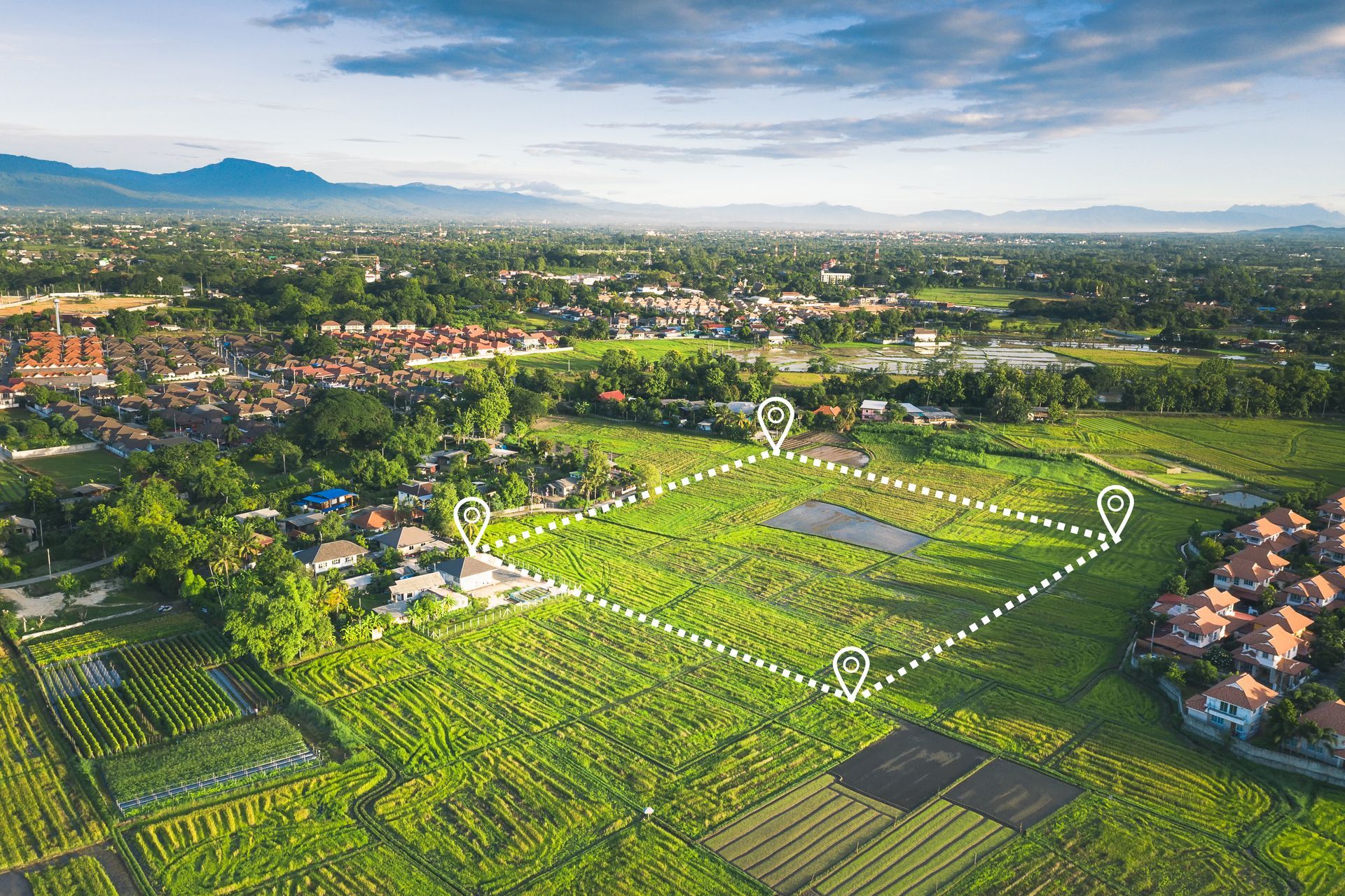 An aerial view of a lush green field with a city in the background.