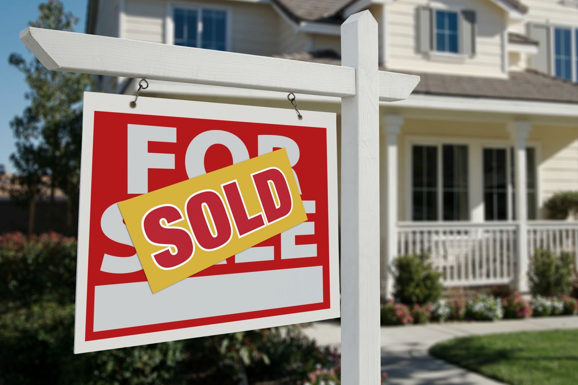 A for sale sign is hanging in front of a house