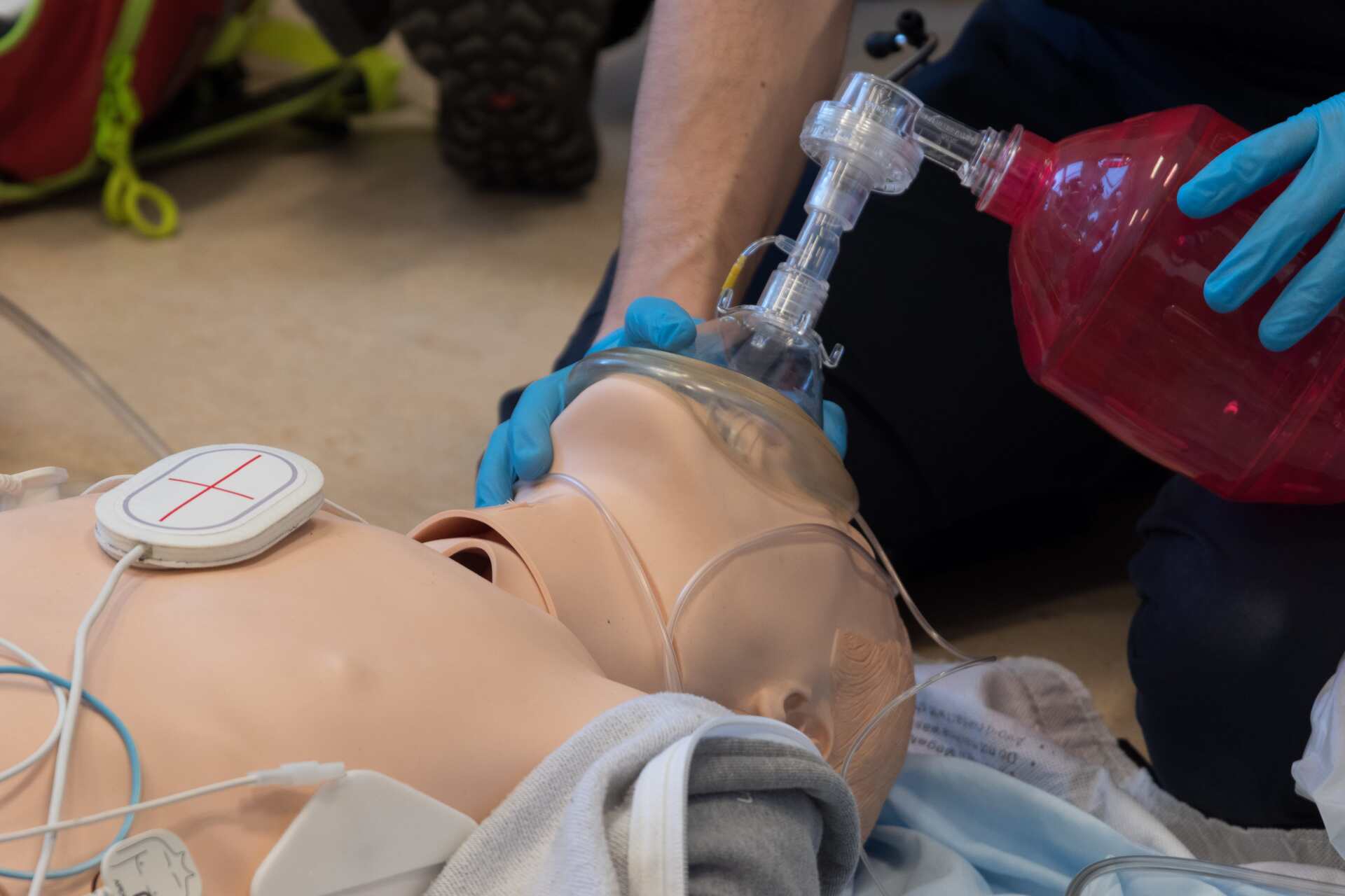 Personne utilisant un masque à valve pour assurer une ventilation artificielle à un mannequin médical ; contexte de formation.