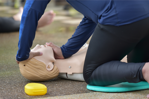 A person is kneeling down next to a mannequin.