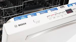 Bosch dishwasher control panel with blue display and white buttons, seen in a kitchen.