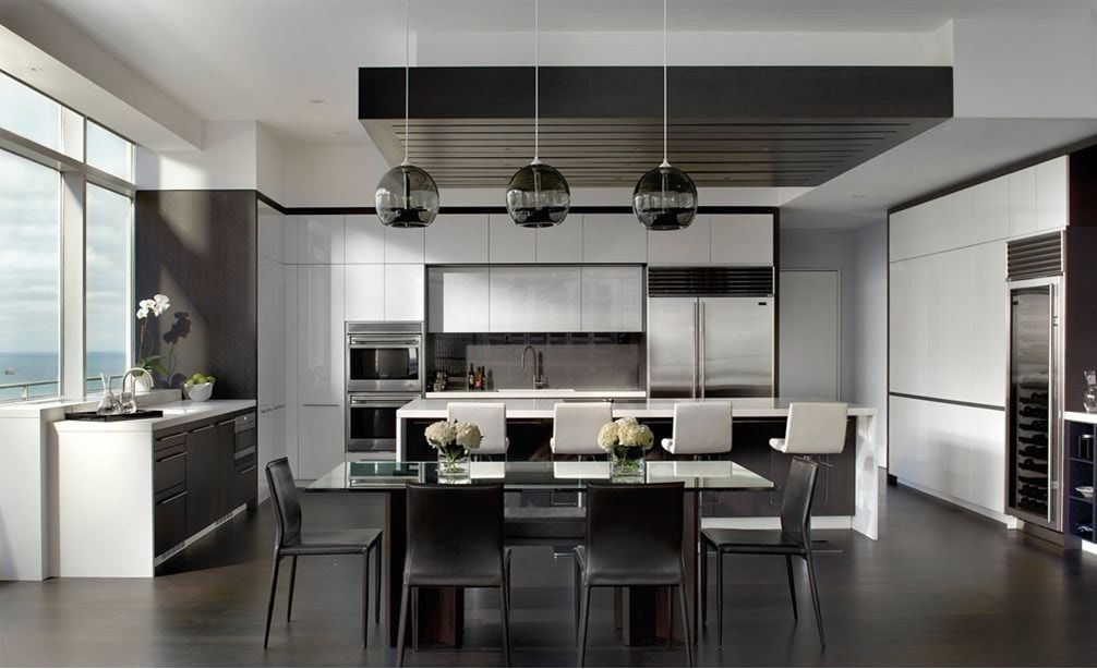 Modern open-concept kitchen and dining area with dark accents, stainless steel appliances, and large windows