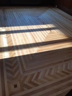 Parquet en chevrons baigné de soleil, avec de fortes ombres de fenêtres
