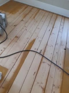 Plancher en bois dans une pièce, avec un câble noir qui traîne sur le sol.
