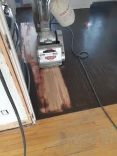 Ponçage d'une bande de parquet usée près d'une porte à l'intérieur d'une pièce.