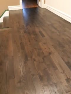 Couloir vide avec parquet foncé et murs blancs