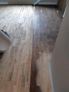 Parquet avec une grande tache foncée dans un couloir ou une pièce lumineuse