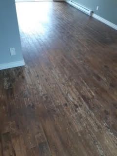 Pièce vide avec parquet sombre et lumière vive entrant par une porte.