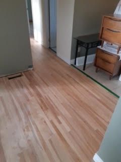 Parquet fraîchement rénové dans un couloir, avec une chaise et une petite table le long du mur.