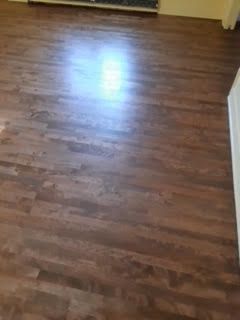 Pièce vide avec parquet en bois brun et un reflet lumineux sur le sol