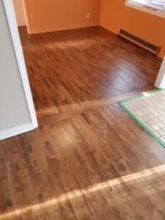 Pièce vide avec parquet, murs orange et un petit tapis près de la porte
