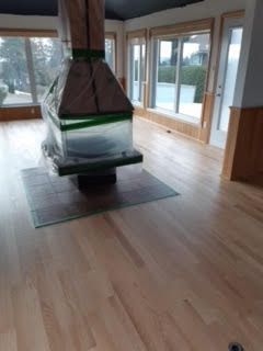 Salon moderne avec cheminée suspendue, parquet et grandes fenêtres donnant sur une terrasse