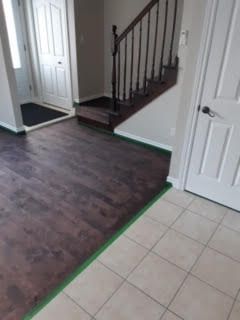 Entrée intérieure avec sol carrelé, parquet foncé et escalier.