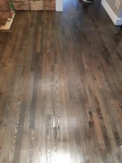 Pièce vide avec parquet foncé et mur en pierre.