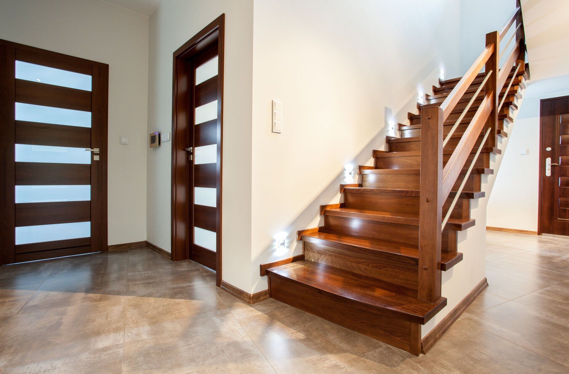 Entrée moderne avec escalier en bois, portes vitrées et sol en pierre polie