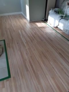 Pièce vide avec parquet clair, contours au ruban adhésif vert et une armoire blanche contre le mur.
