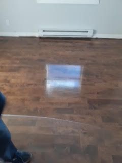 Pièce vide avec parquet, mur blanc, radiateur plinthe et un léger reflet sur le sol