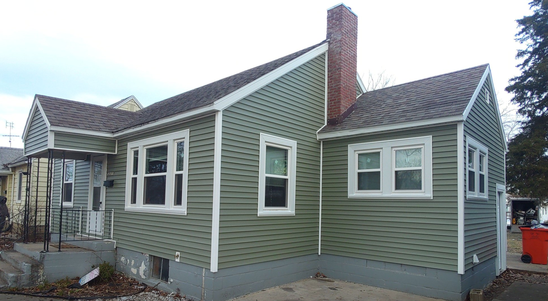 A green house with a chimney and a lot of windows