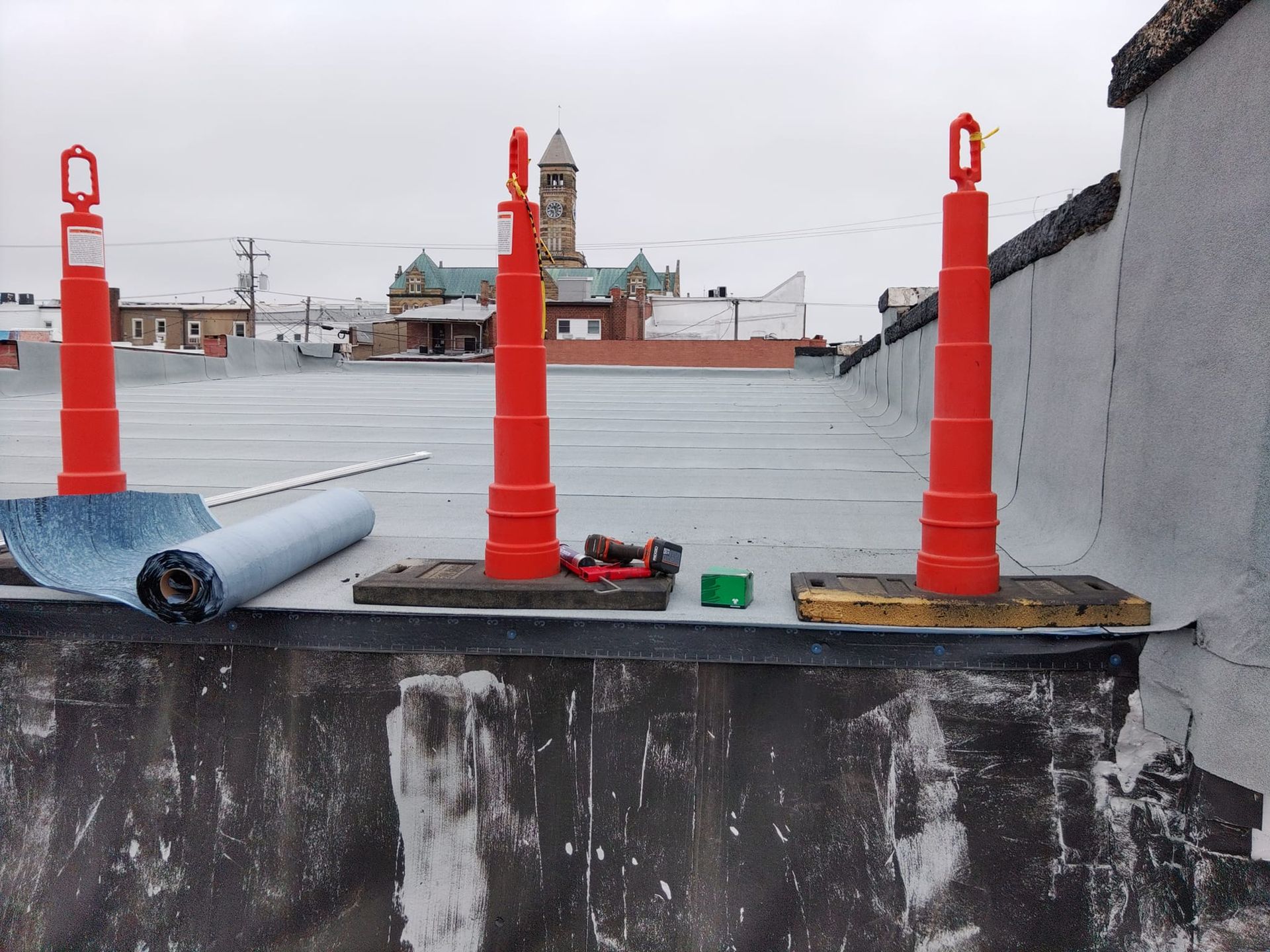 Three orange cones are sitting on top of a roof