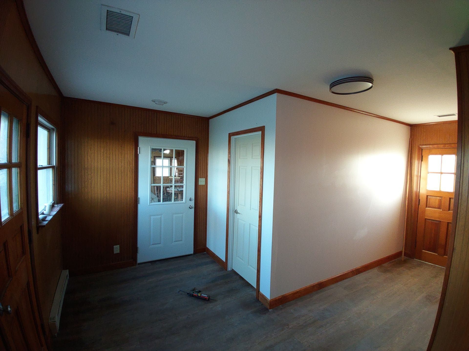 An empty room with wood paneling and a white door.