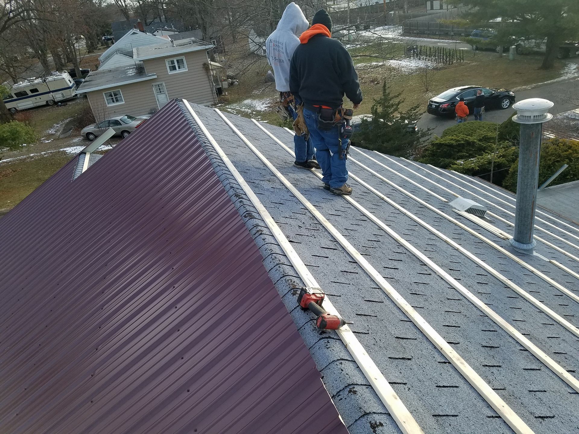 Two men are working on the roof of a house