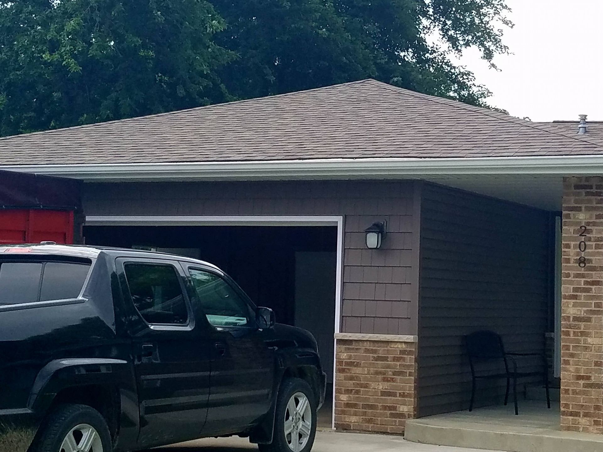 A black truck is parked in front of a brick house