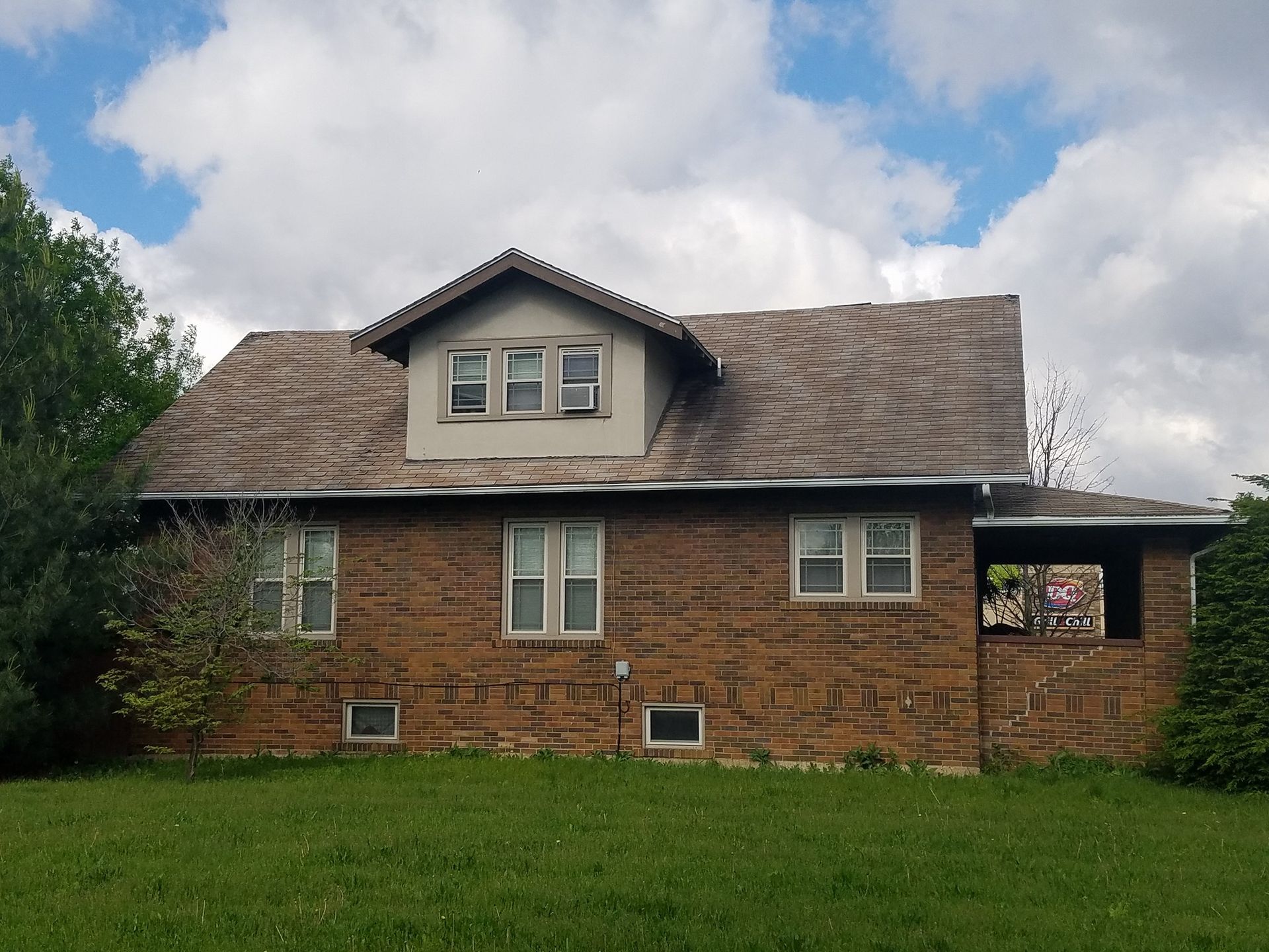 A brick house with a roof that has shingles on it