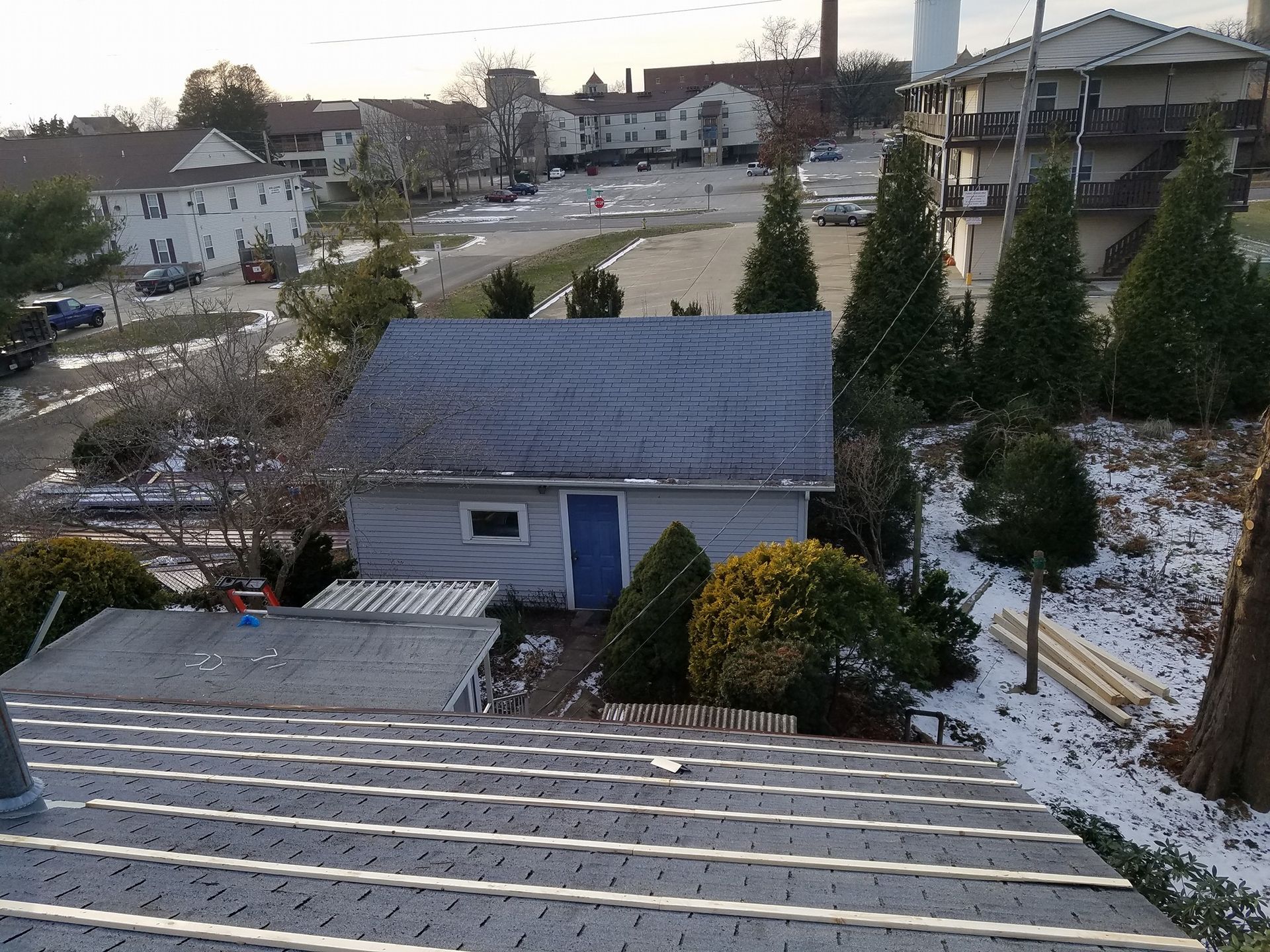 A small house with a blue door sits in the middle of a snowy yard