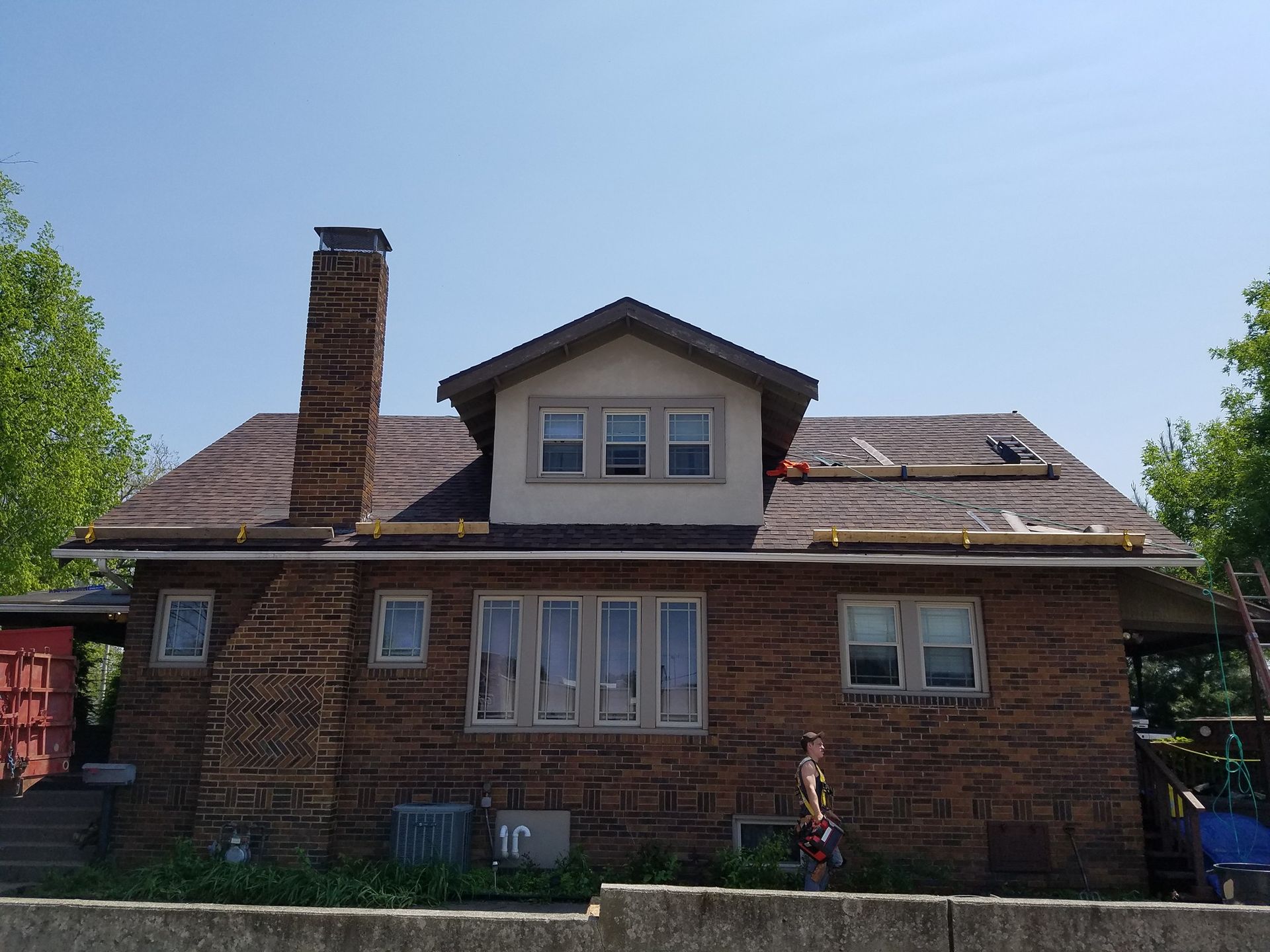 A brick house with a roof that is being repaired
