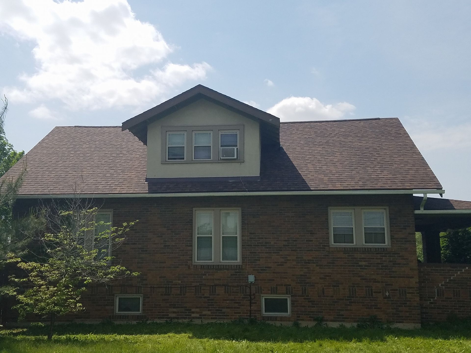 A brick house with a brown roof and white trim