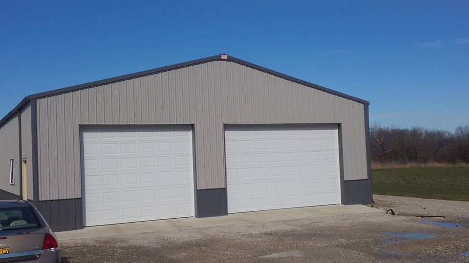 A garage with two garage doors and a car parked in front of it.