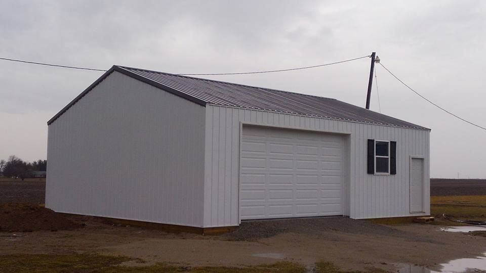 A white garage with a gray roof and black shutters