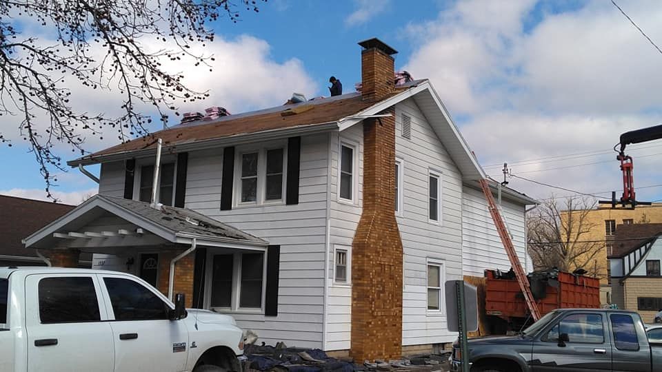 A white truck is parked in front of a house under construction.