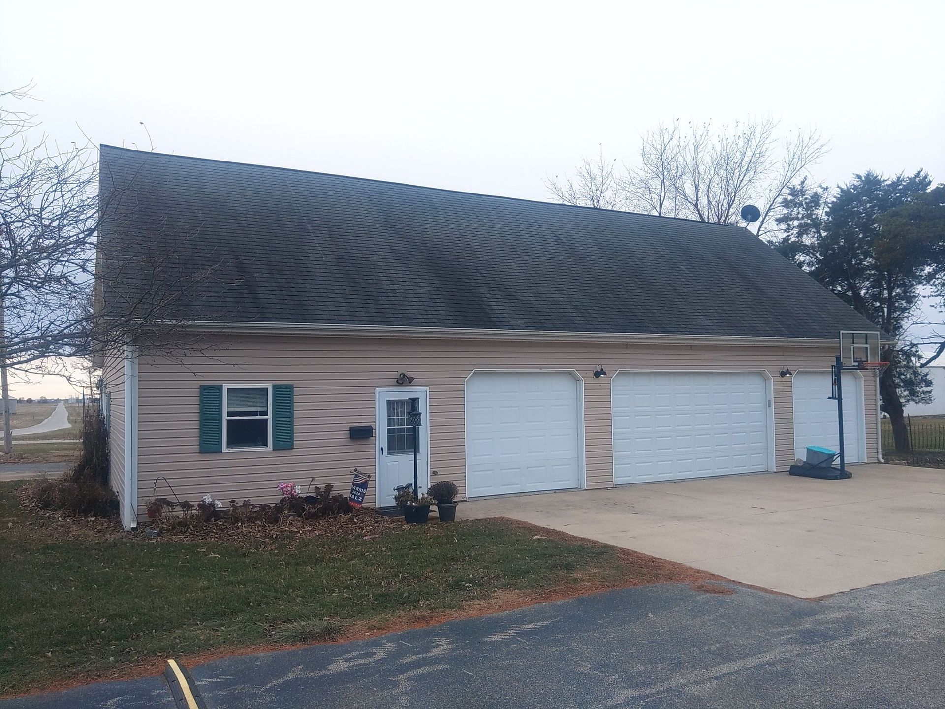 A house with three garage doors and a basketball hoop in front of it