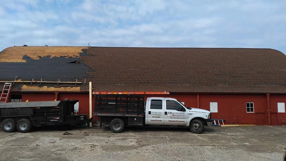 A white truck is parked in front of a red building.