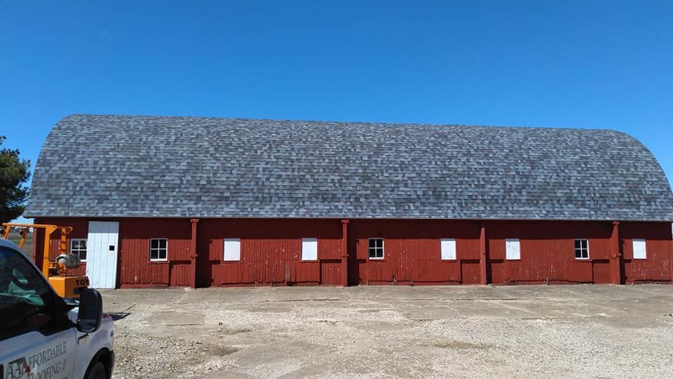 A red barn with a white truck parked in front of it.