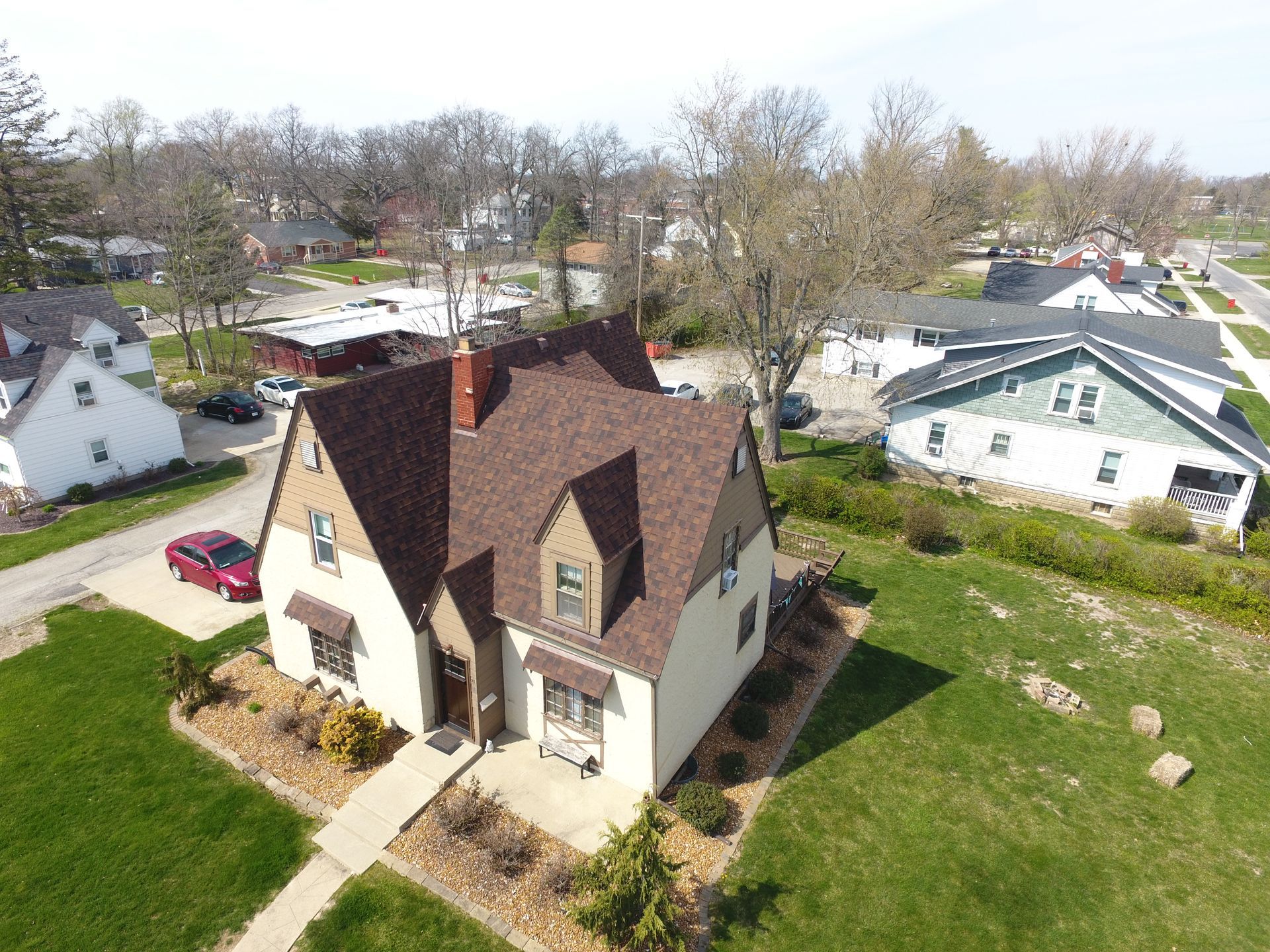 An aerial view of a house with a brown roof in a residential area.