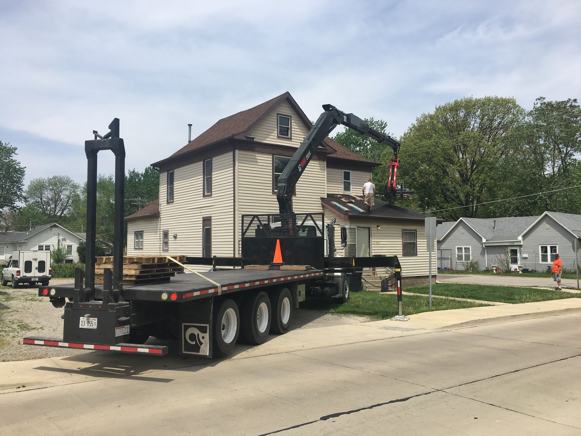 A truck with a crane on the back is parked in front of a house.