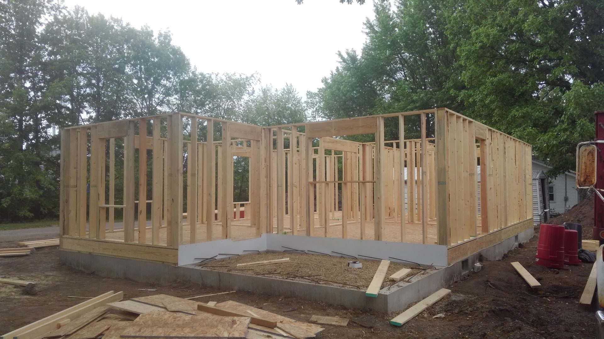 A wooden house is being built in the middle of a field.