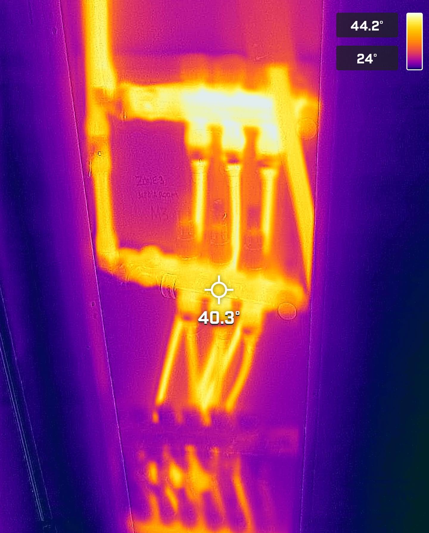 Thermal image of electrical wiring; warm areas highlighted in orange/yellow, indicating heat. Temperature readings displayed.