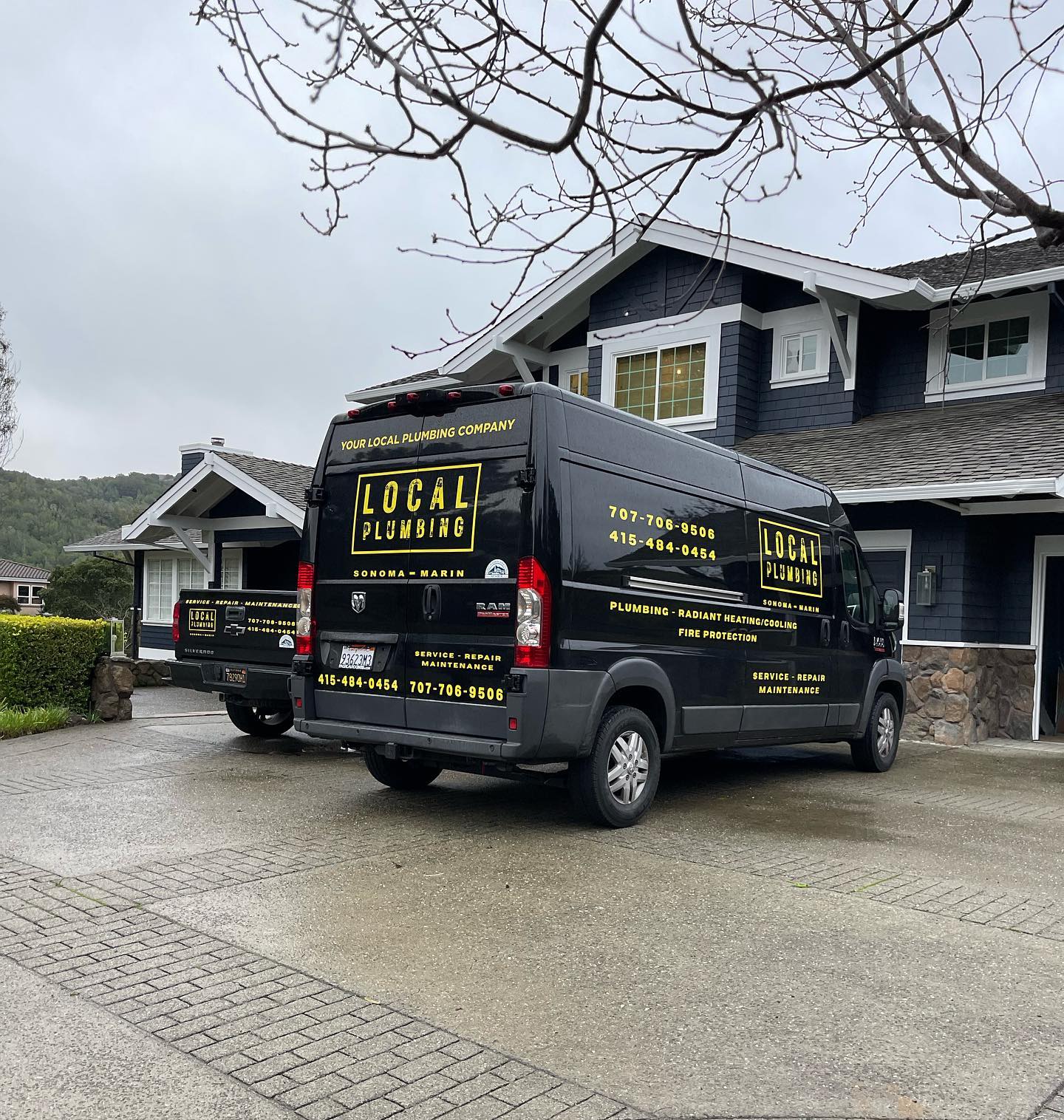 Black plumbing van parked in front of a house. 