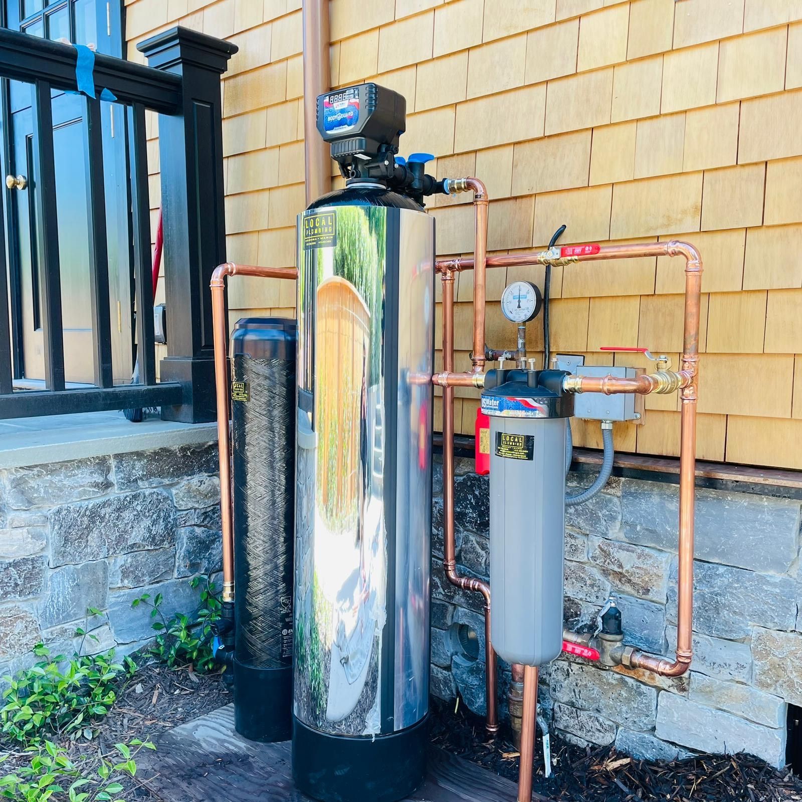 Water filtration system with copper piping, installed outside a home.