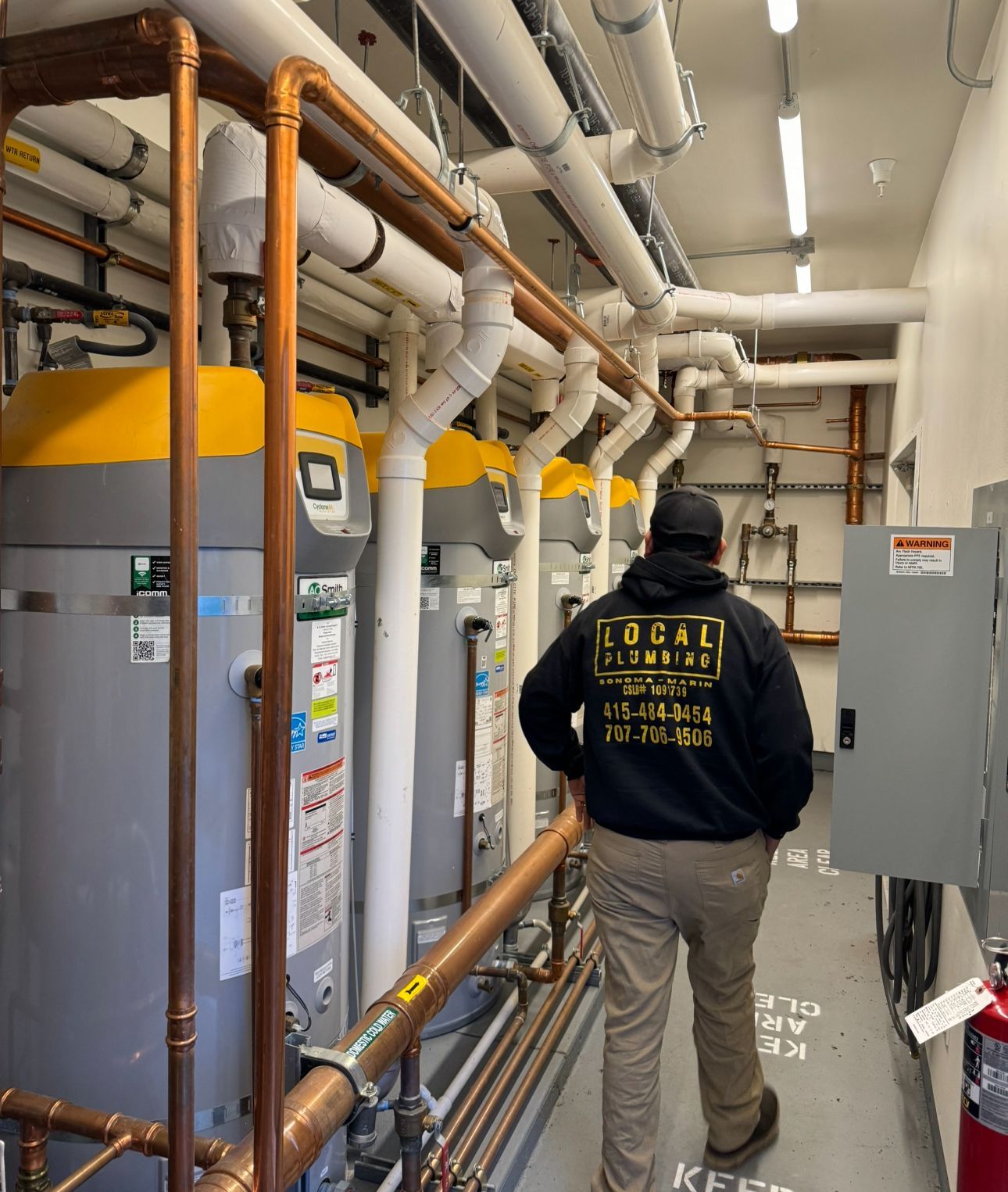 Plumber in a mechanical room with copper pipes and water heaters.