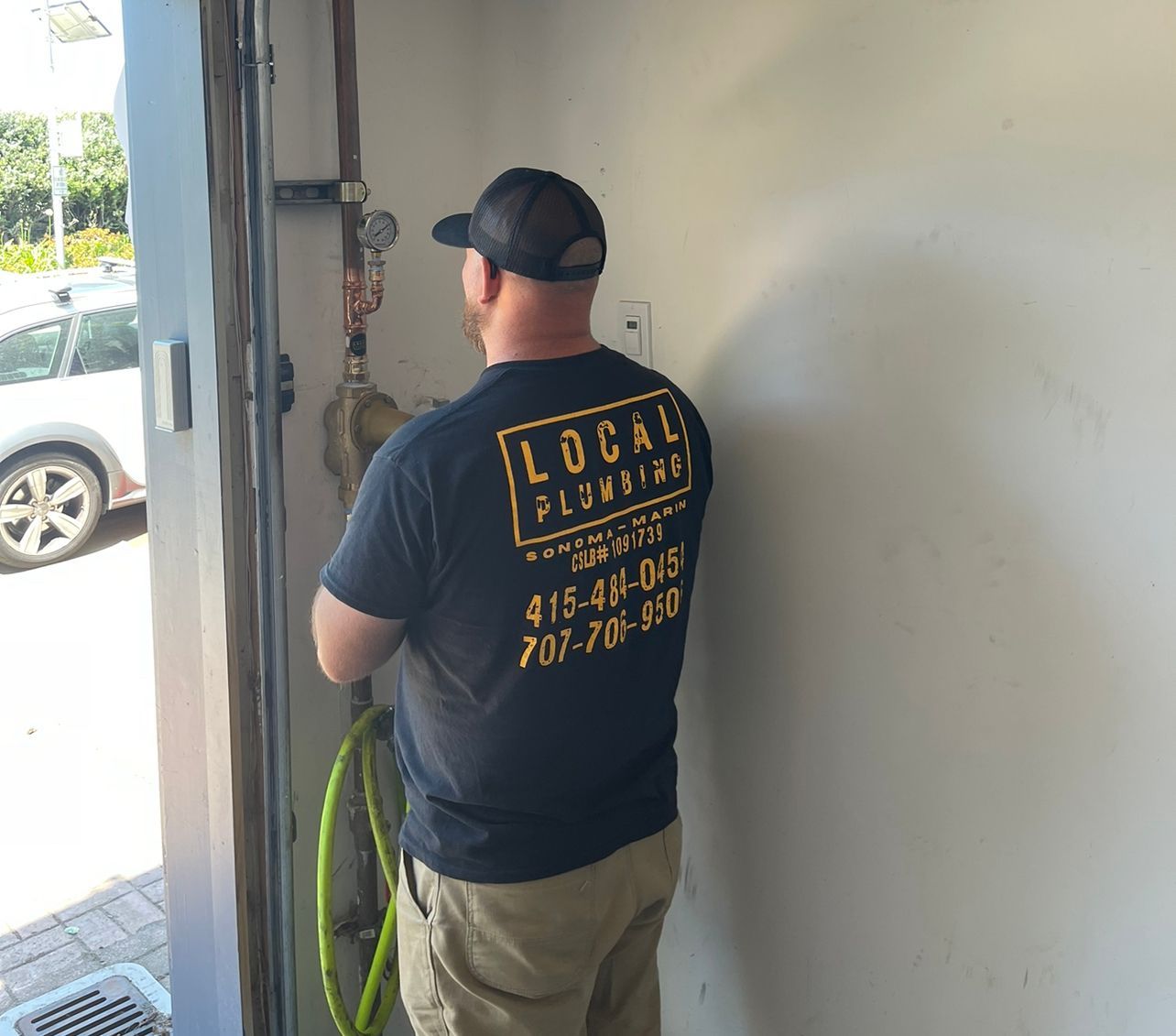 Plumber in corner of garage area locating the water shut off