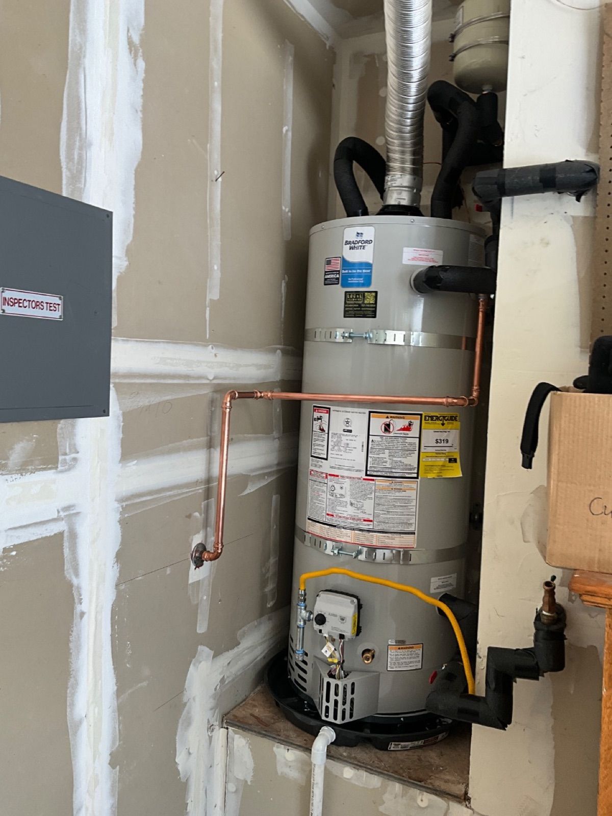 Bradford White gas water heater installed by Local Plumbing in a garage alcove, strapped and repiped in copper