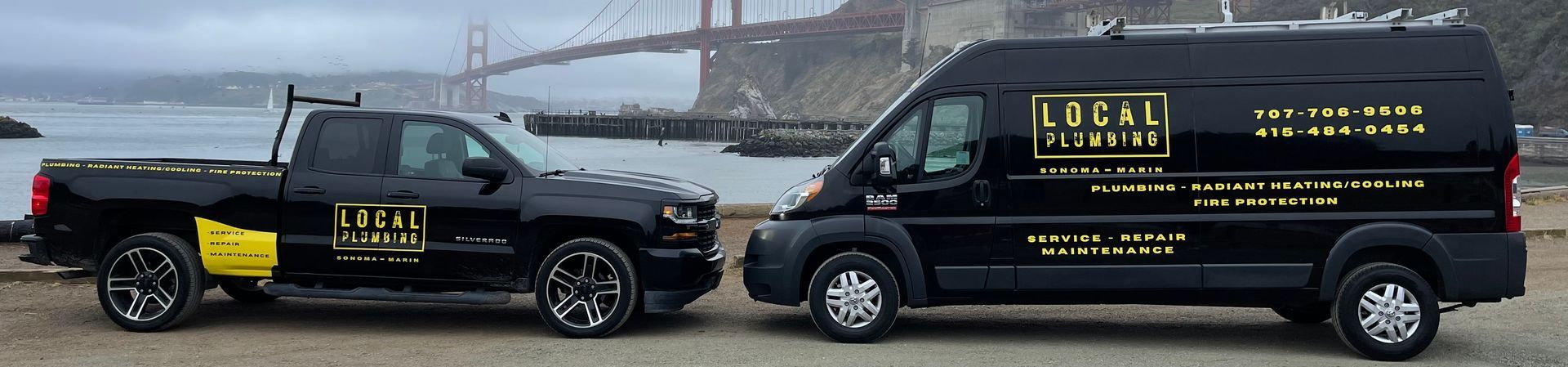 Black pickup truck and van parked with Golden Gate Bridge in the background. Logos on vehicles.