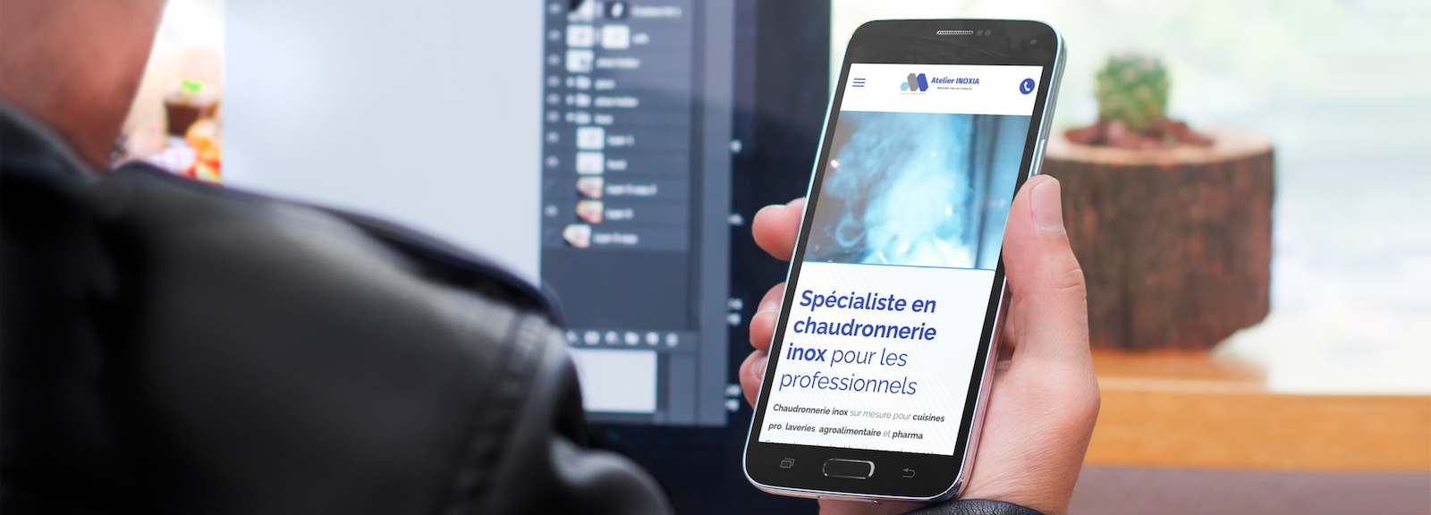 Une personne tient un téléphone portable dans sa main devant un écran d'ordinateur.