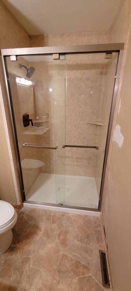 Bathroom with glass shower doors, tiled floors, and toilet.