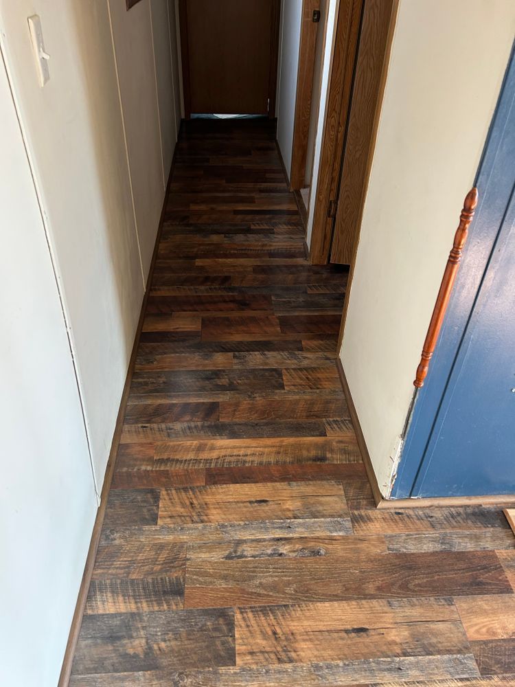 Narrow hallway with wood-look flooring, white walls, and a blue door.